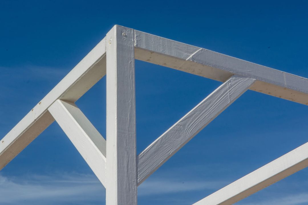 Weiß gestrichene Holzstütze mit zwei Kopfbändern, die einen Träger stützen
