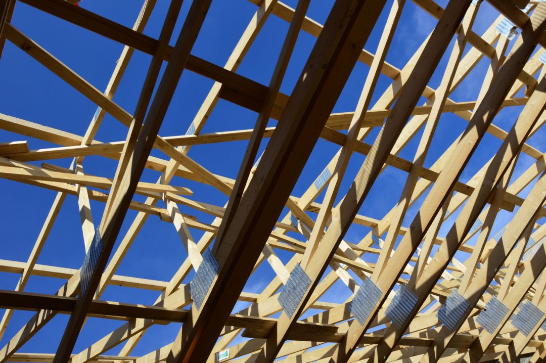 Dachbinder aus Holz mit sichtbaren metallenen Knotenblechen gegen blauen Himmel